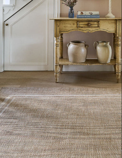 Foyer with a wooden console table, decorative items, and a textured rug.